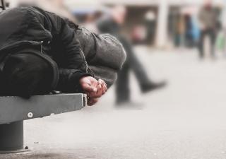 homeless man asleep on bench